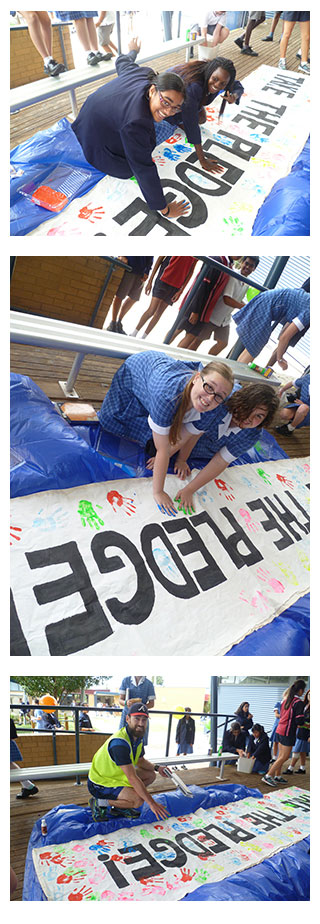 Image of Students stamping their painted handprints on a giant mural after committing to stand together against bullying.
